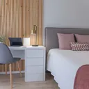 Bright studio bedroom with a desk and pink bedding.
